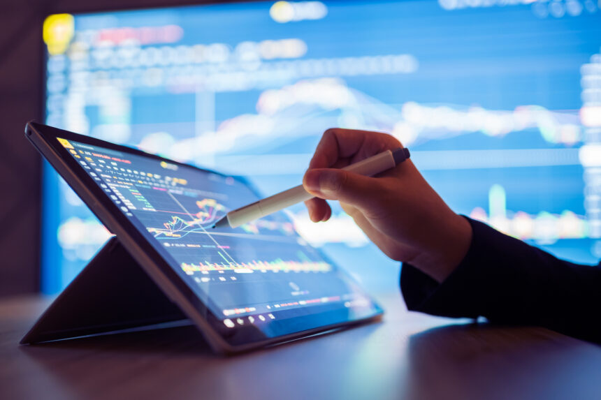 a person using a pen to point at a stock chart on a tablet