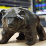 bear in front of stocks on screen