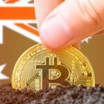 hand holding a bitcoin above soil with an australian flag background