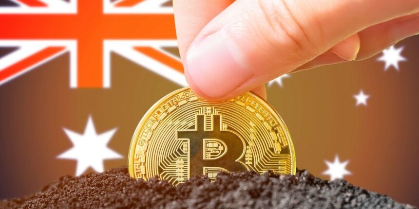 hand holding a bitcoin above soil with an australian flag background