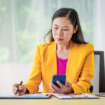 investor at desk considers phone and papers