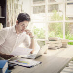 investor considers papers while sitting near books