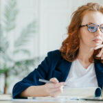 investor considers screen while writing on pad