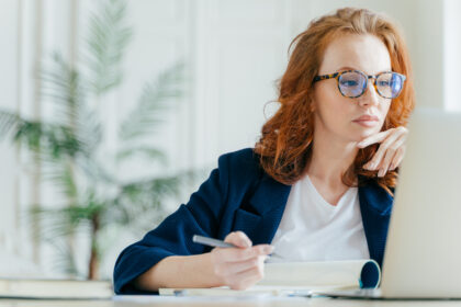 investor considers screen while writing on pad
