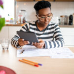 investors considers papers on a table while holding a tablet