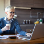 investors drinks and examines laptop
