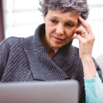 person with a worried expression looking at a laptop copy