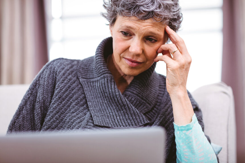 person with a worried expression looking at a laptop copy