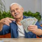 pointing to hundred dollar bills with a smile 2155653655