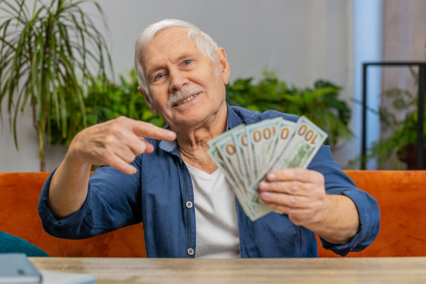 pointing to hundred dollar bills with a smile 2155653655