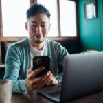 stock market investor person looking at smartphone and laptop
