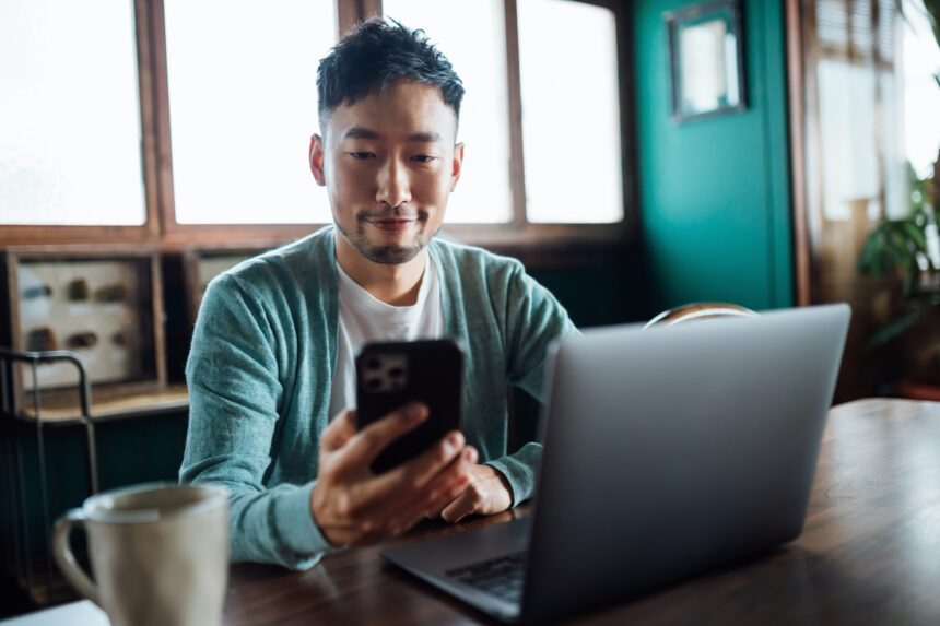 stock market investor person looking at smartphone and laptop
