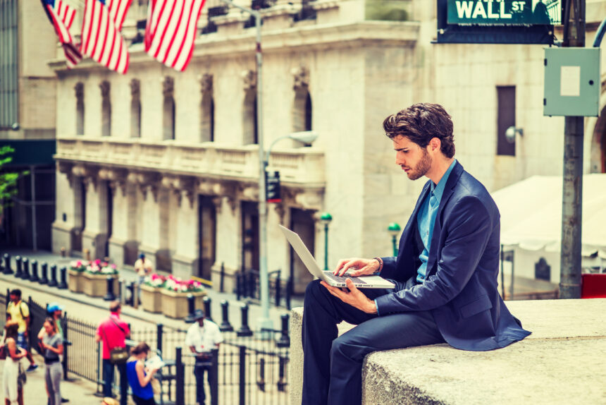 trader with laptop on wall street
