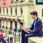 trader with laptop on wall street