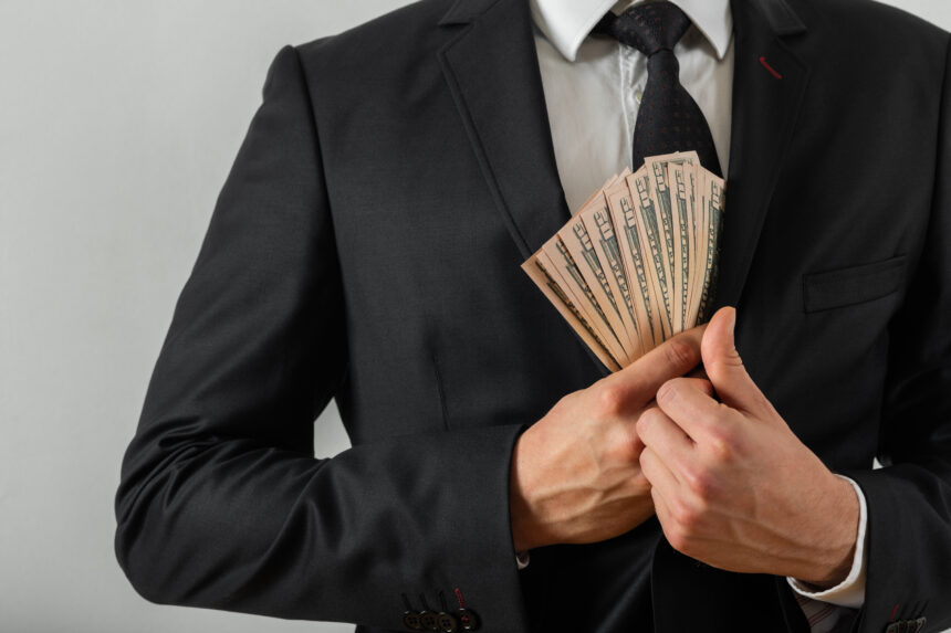 wealthy person putting cash in their suit pocket