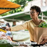 SOCIAL IMAGE PARTNER OFFER TERMS APPLY woman paying with mobile phone at a street market FG Trade 17