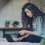 Woman on bed with credit card and laptop