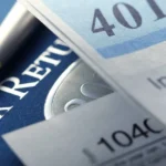 a 401k statement rests on top of a us federal 1040 income tax return and is photographed using a ver